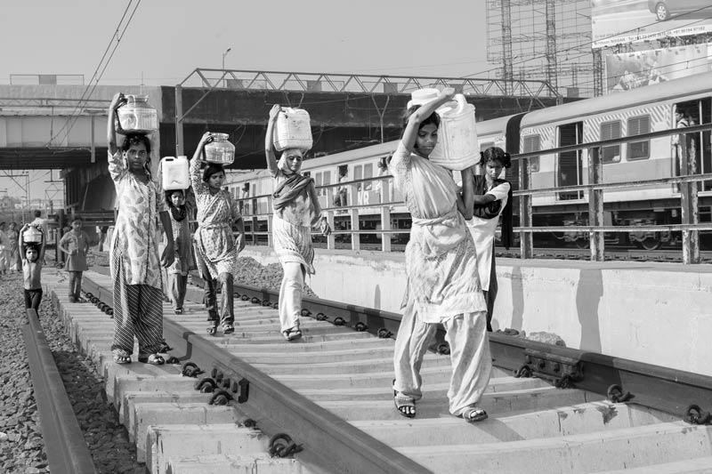 Human Right to Water in Mumbai - Returning home with loads of 'spring' water sourced from a water mains leakage across busy railway tracks